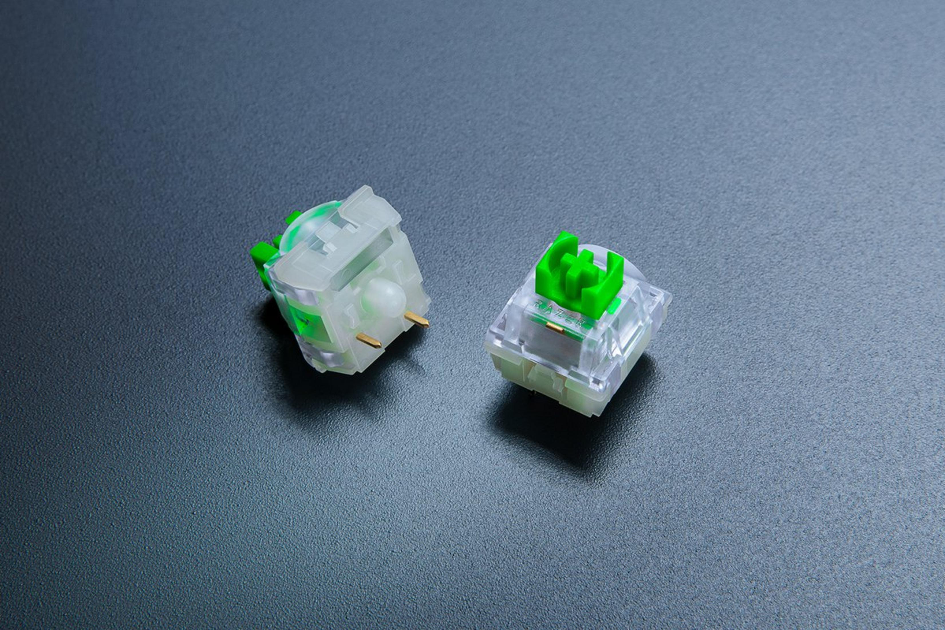 Dos interruptores de teclado mecánico transparentes con detalles verdes sobre una superficie oscura.