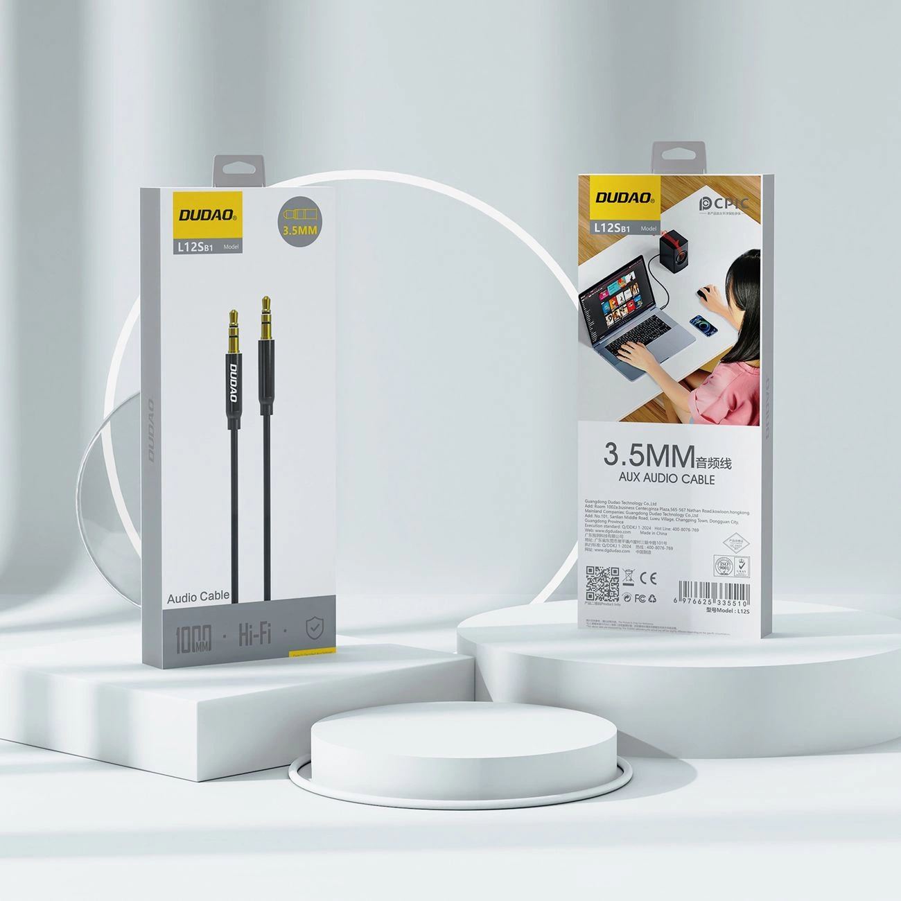 Due scatole di cavi audio AUX Dudao da 3,5 mm su podi bianchi con sfondo chiaro.