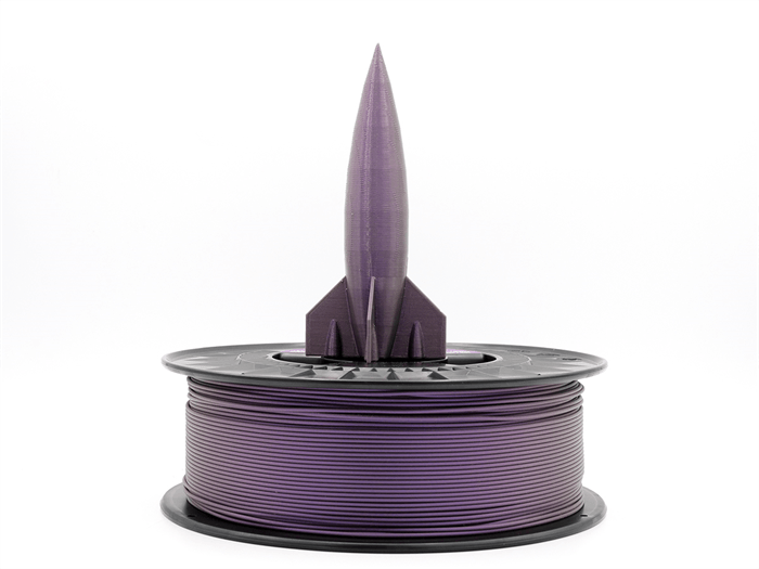 Un razzo stampato in 3D viola si trova su una bobina di filamento viola su sfondo bianco.