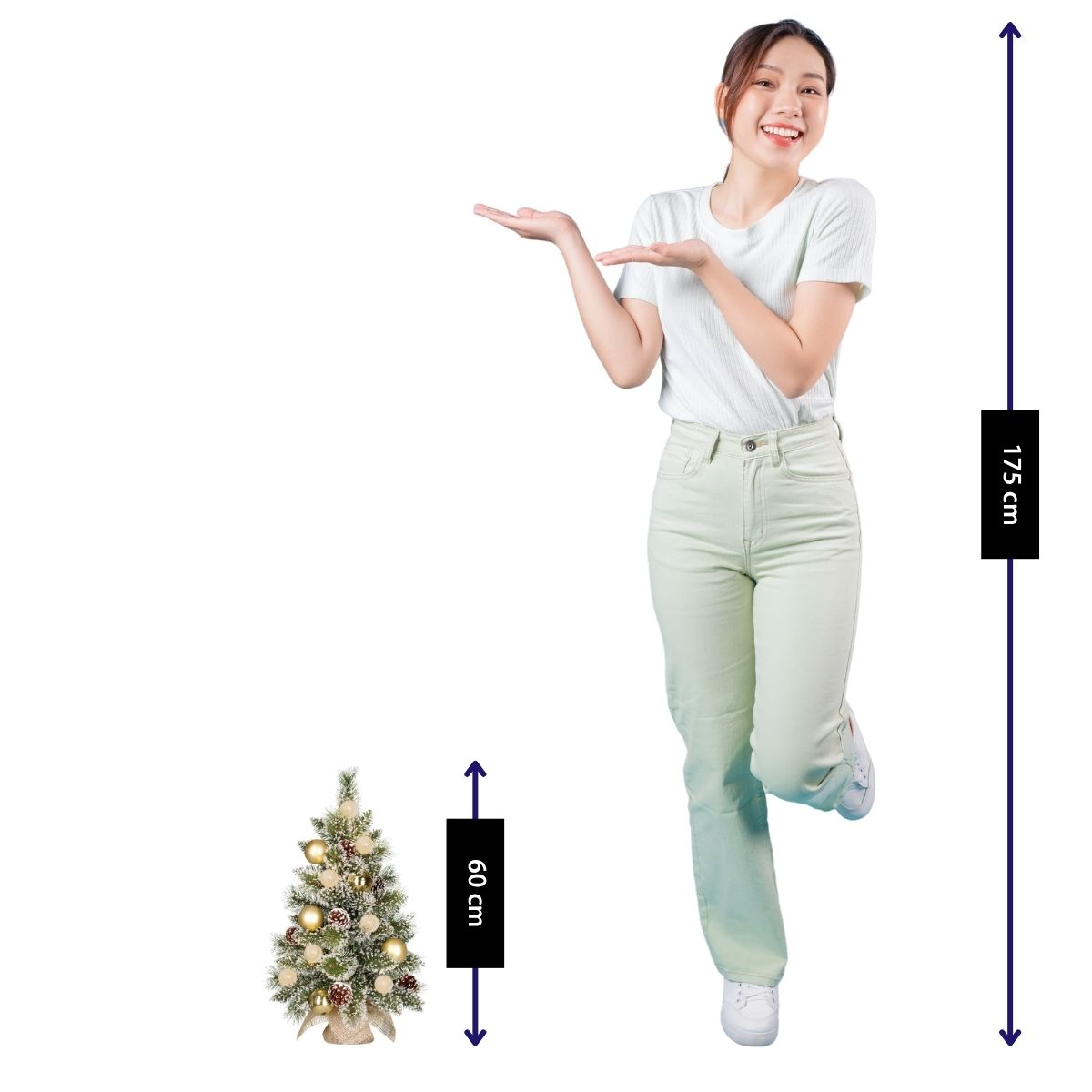 Eine Frau in weißem Shirt und heller Hose steht neben einem 60 cm kleinen Weihnachtsbaum und zeigt auf die Größe.
