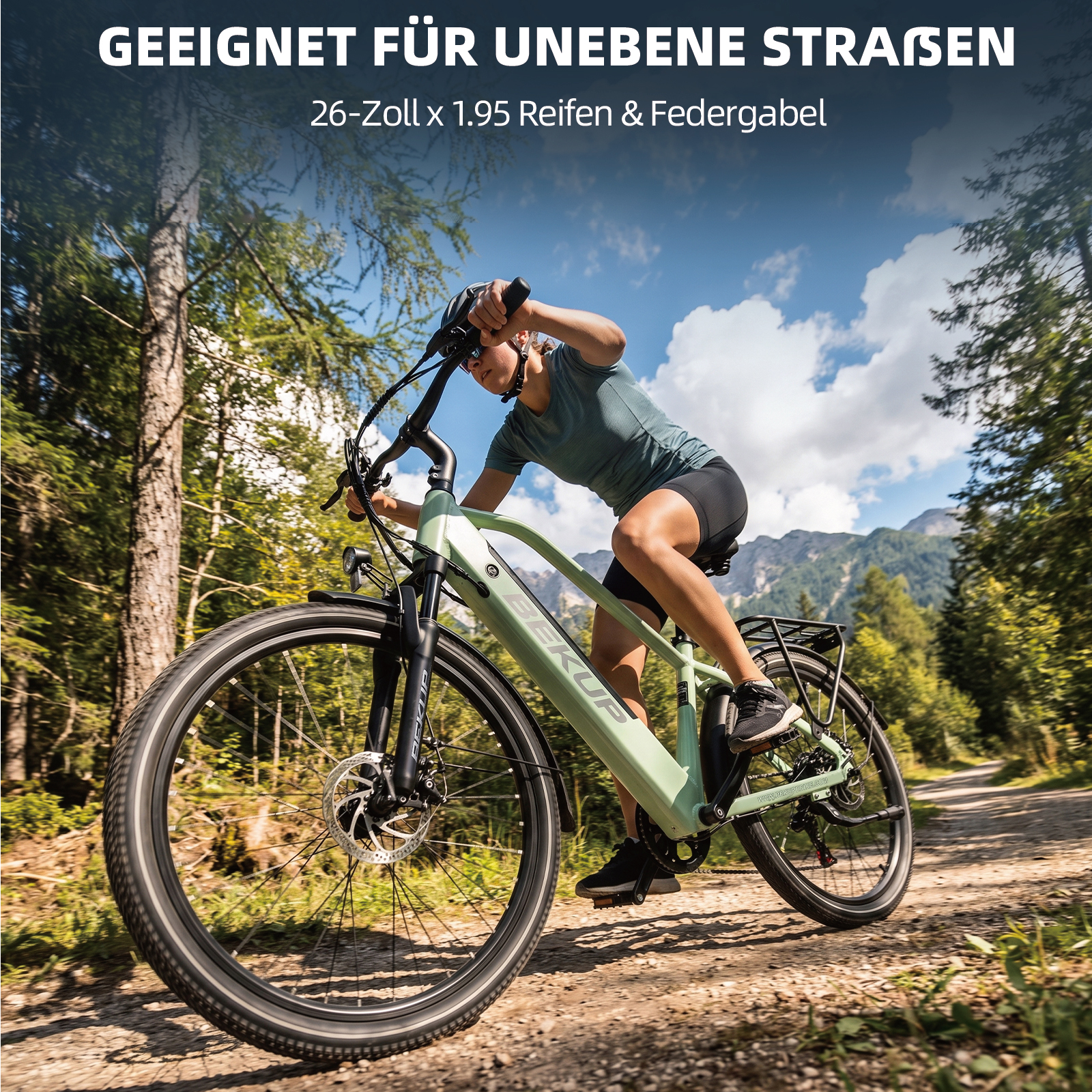 Eine Frau fährt ein hellgrünes Elektrofahrrad auf einem sonnigen Schotterweg durch einen Wald mit Bergen im Hintergrund.