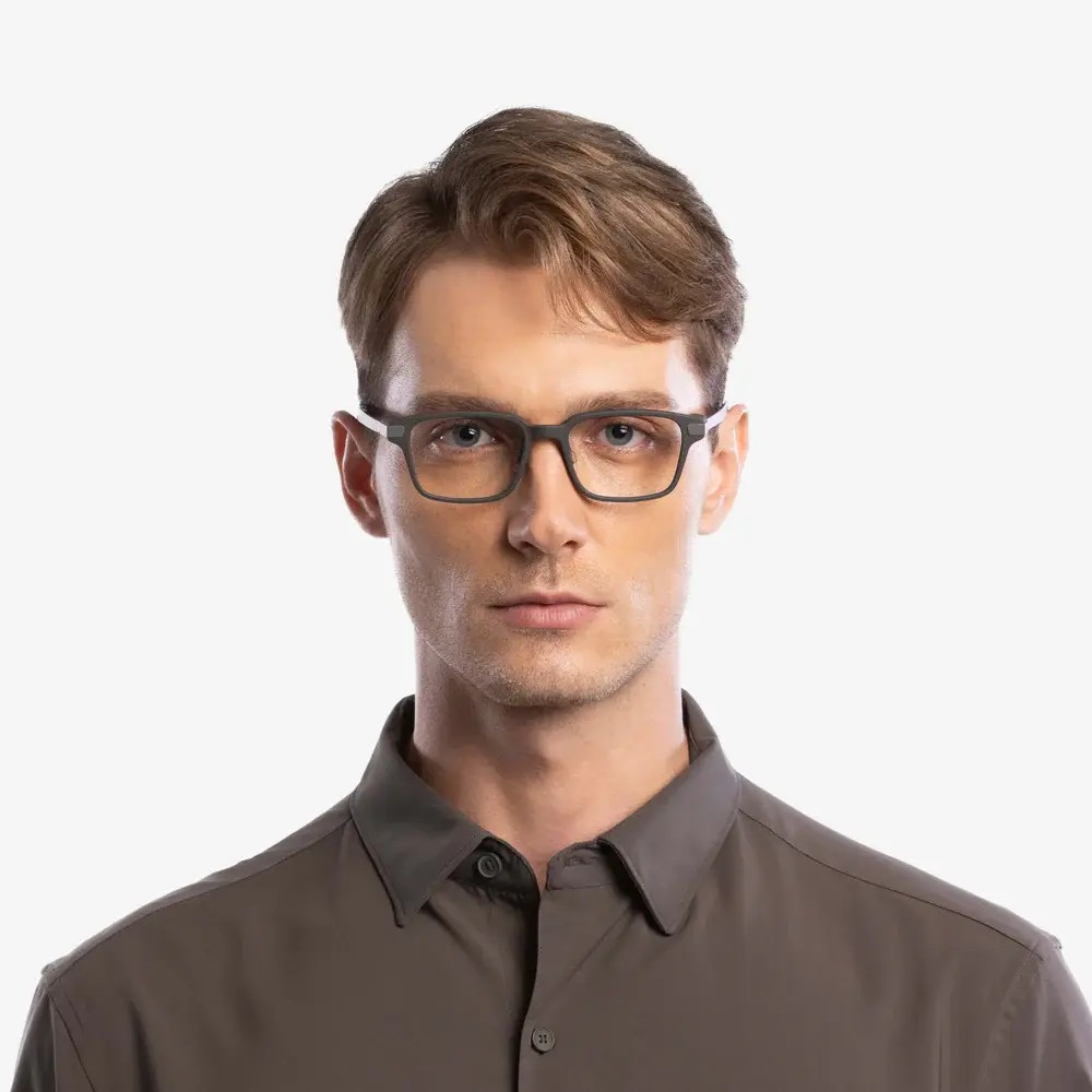 Un hombre con gafas gris oscuro y camisa a juego sobre fondo blanco.