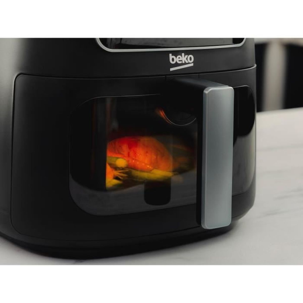Une friteuse à air Beko noire avec une fenêtre éclairée montrant des aliments à l'intérieur sur un plan de travail.