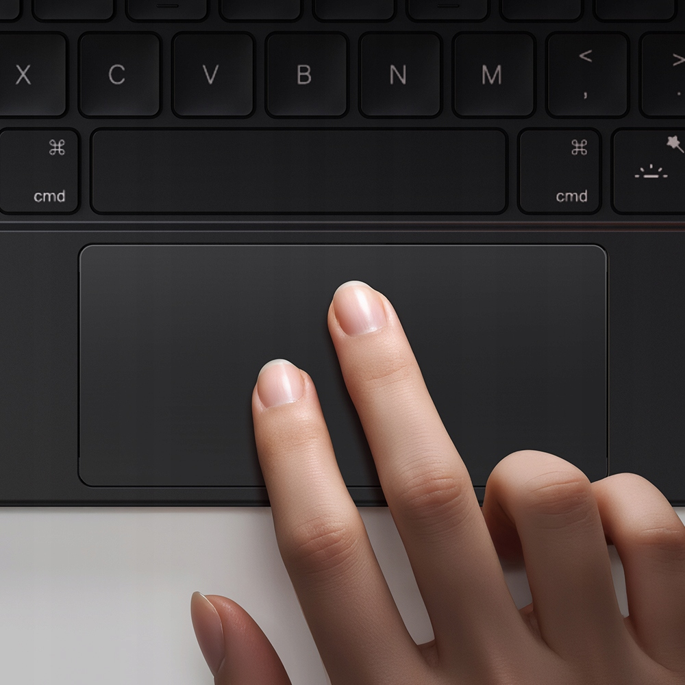 Una mano tocca il trackpad di una tastiera nera con due dita.