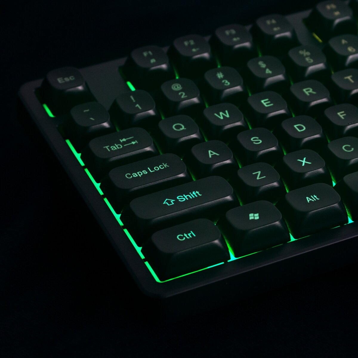 Una tastiera per computer nera con retroilluminazione verde brillante su sfondo scuro.