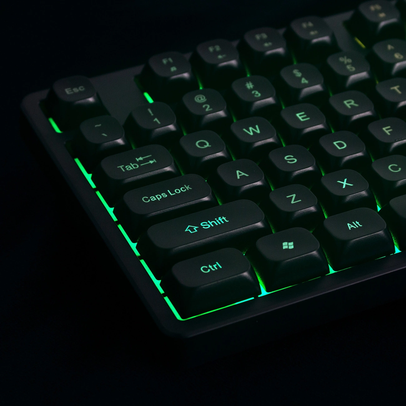 Una tastiera per computer nera con retroilluminazione verde brillante su sfondo scuro.
