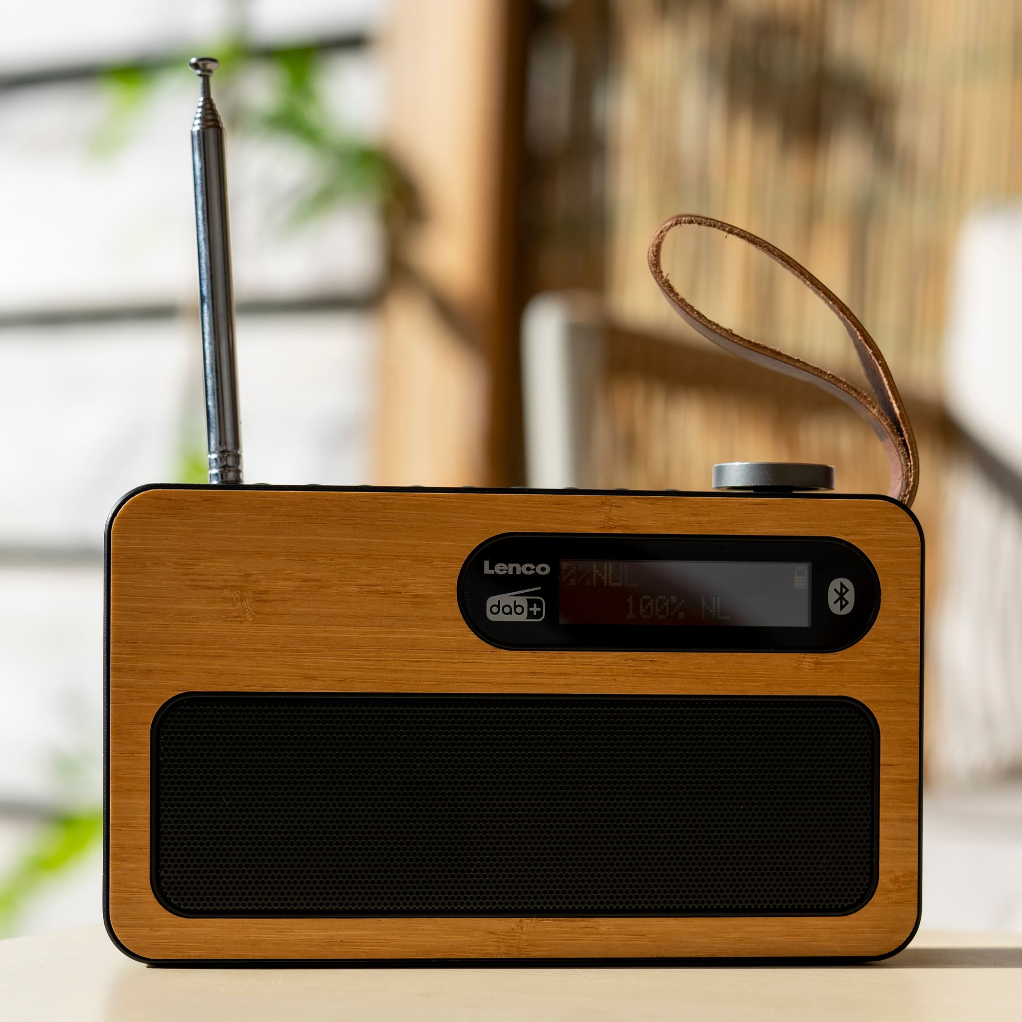 Ein tragbares Holaradio mit schwarzem Lautsprechergitter, ausziehbarer Antenne und Lederriemen.