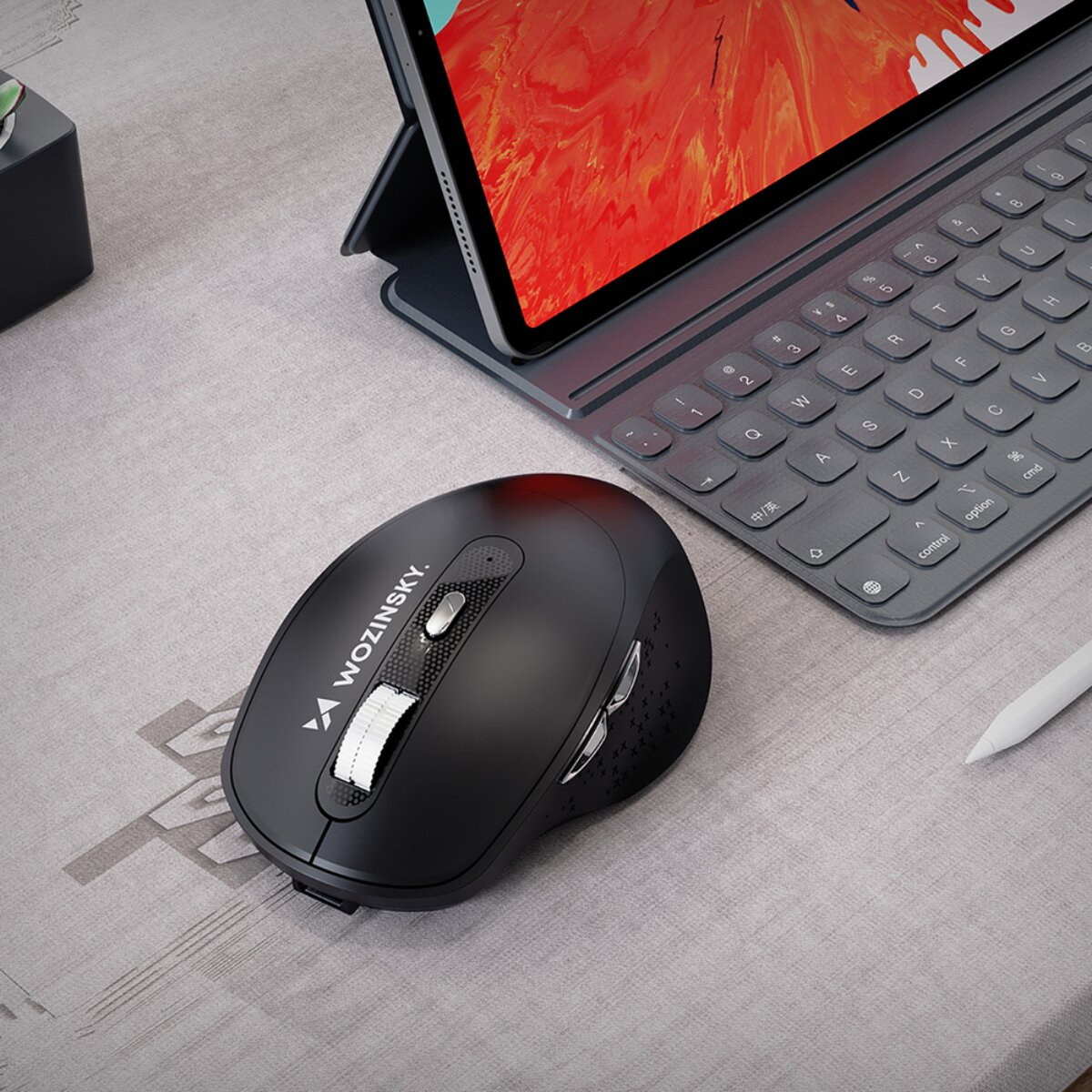 Un mouse nero Wozinsky si trova su una scrivania vicino a una tastiera e a un tablet.
