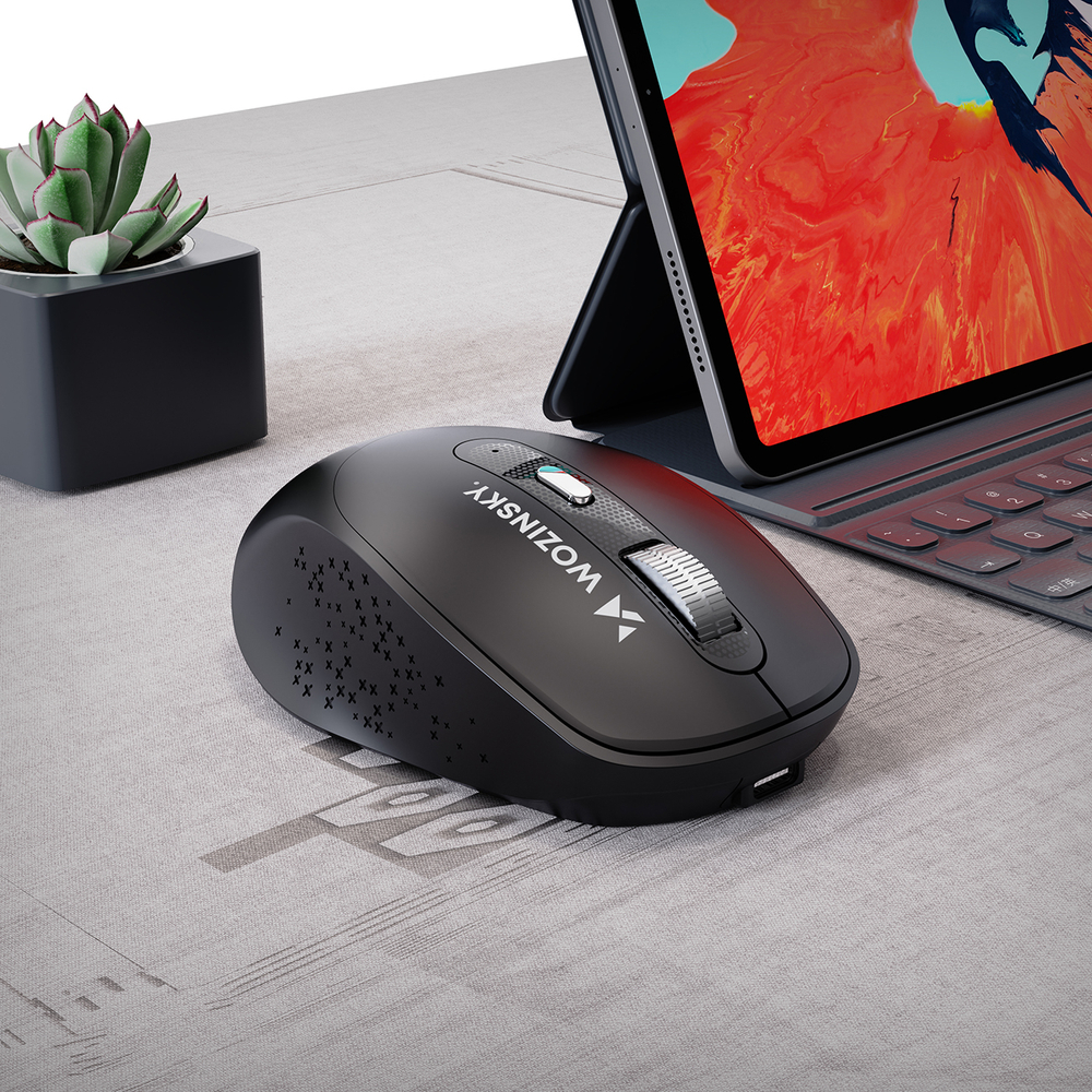 Un mouse nero Wozinsky su una scrivania vicino a un tablet e a una piccola pianta.