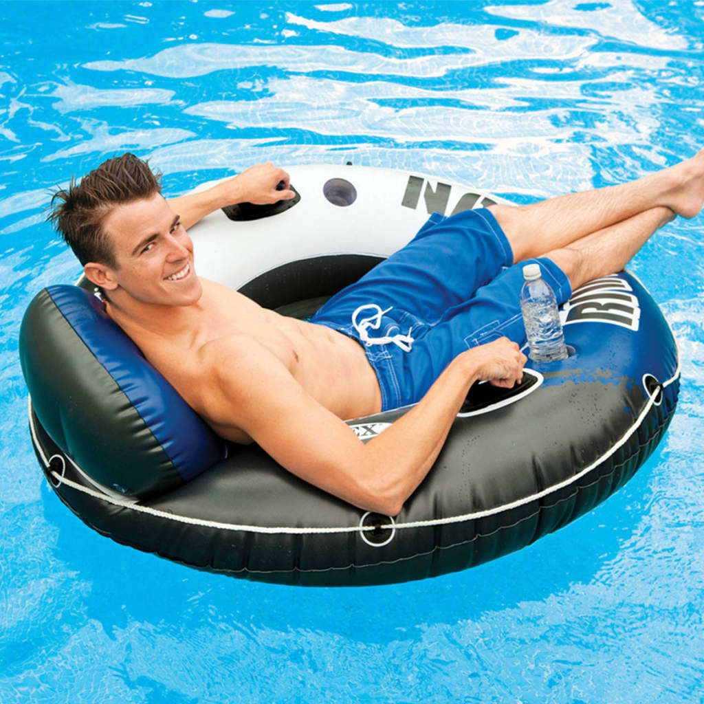 Ein Mann entspannt sich auf einem schwarzen und weißen Schlauchboot in einem blauen Pool und hält eine Wasserflasche.