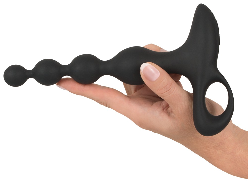 Eine Hand hält ein schwarzes Wellnessgerät mit Kugeln und einem Griff gegen einen weißen Hintergrund.