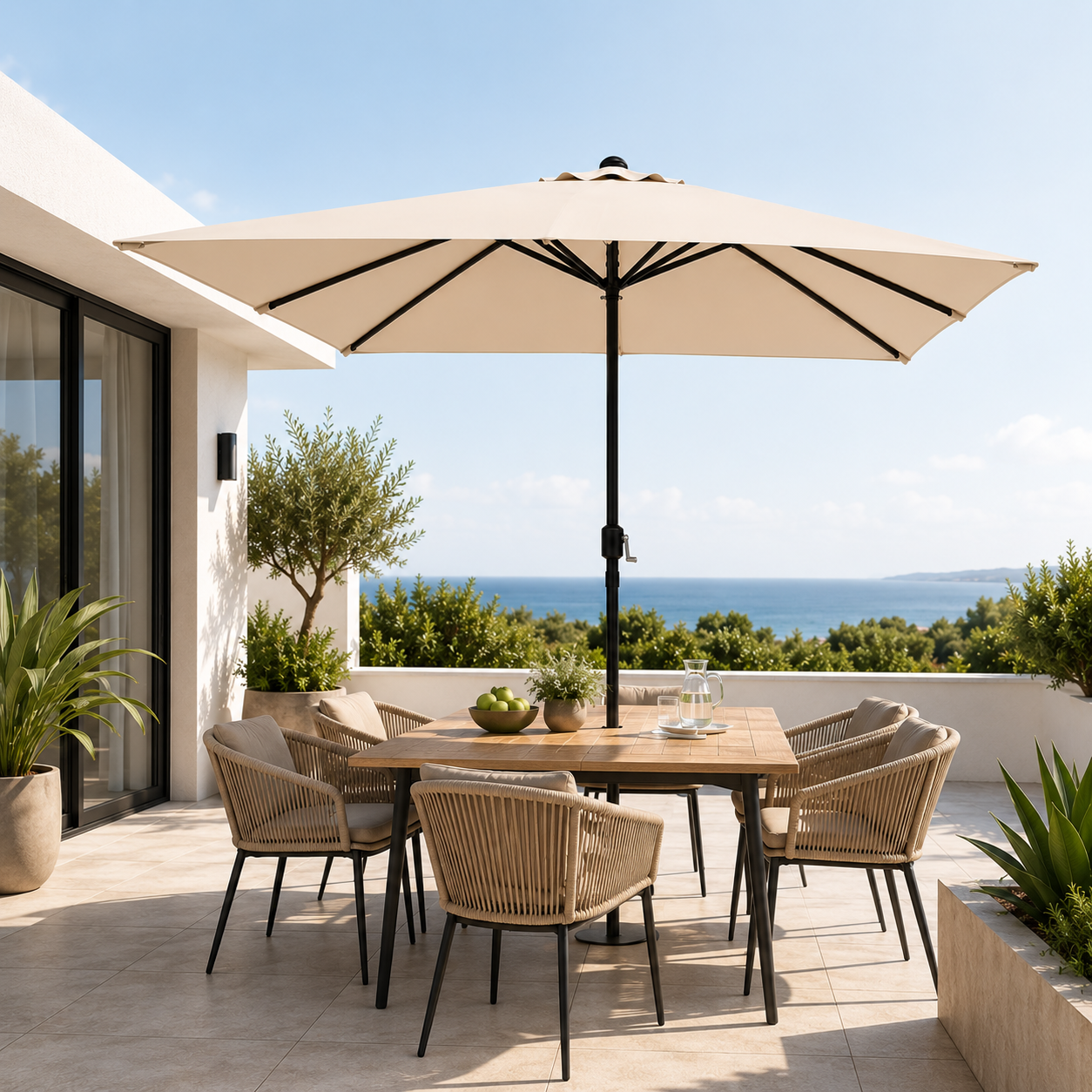 Una terraza soleada junto al mar con una gran sombrilla cuadrada, una mesa de madera y sillones de mimbre.