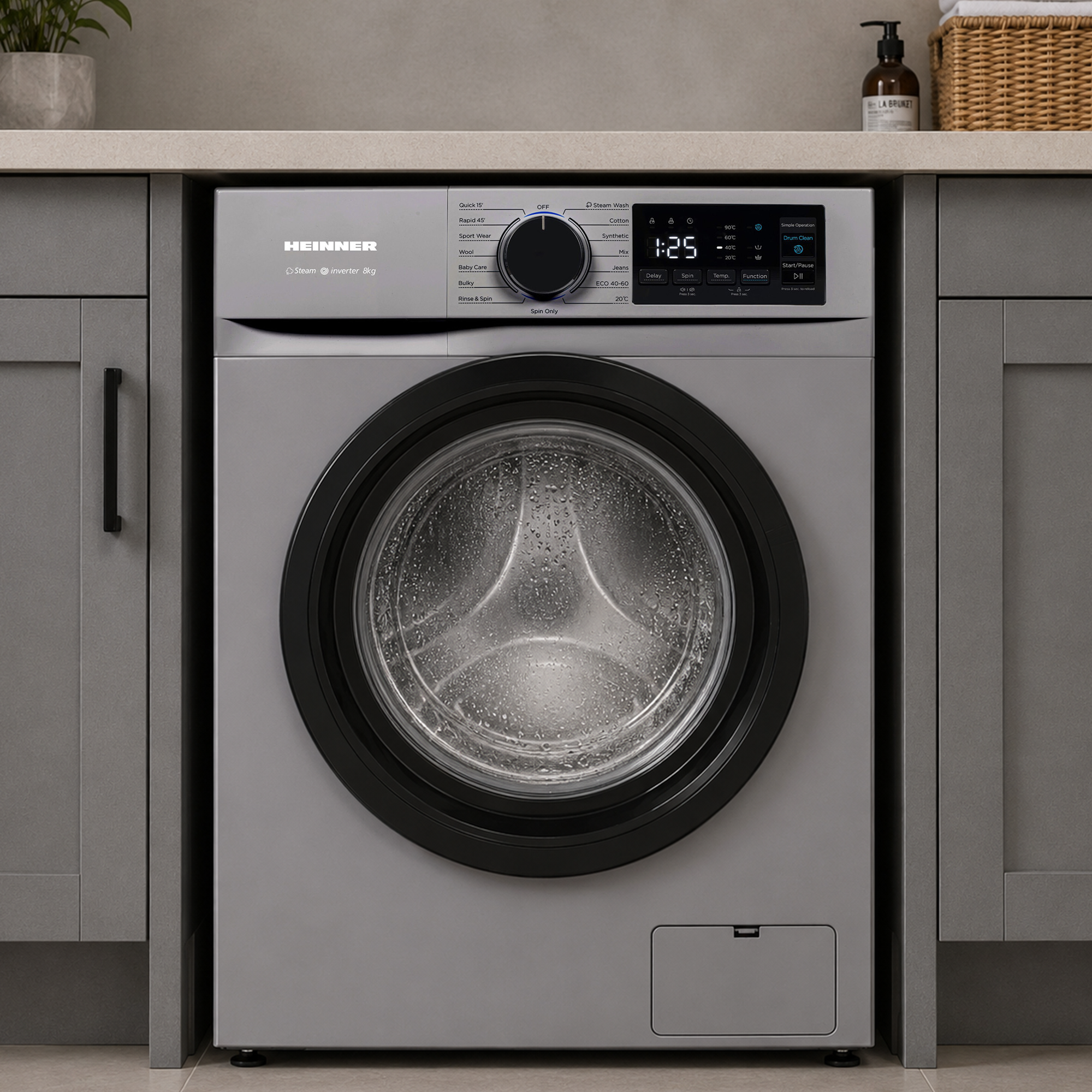 Eine graue Heinner Waschmaschine steht unter einer Küchentheke mit grauen Schränken.