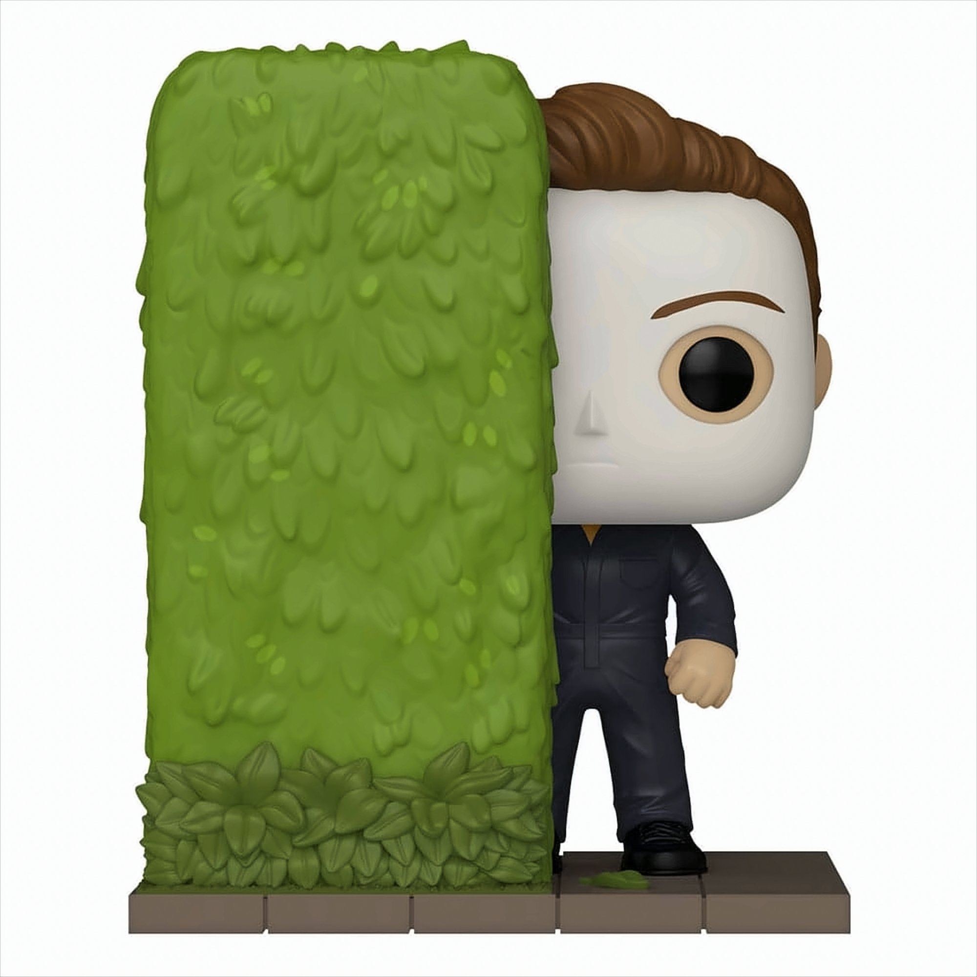 Eine Michael Myers Funko Pop Figur schaut aus der Deckung einer grünen Hecke hervor.