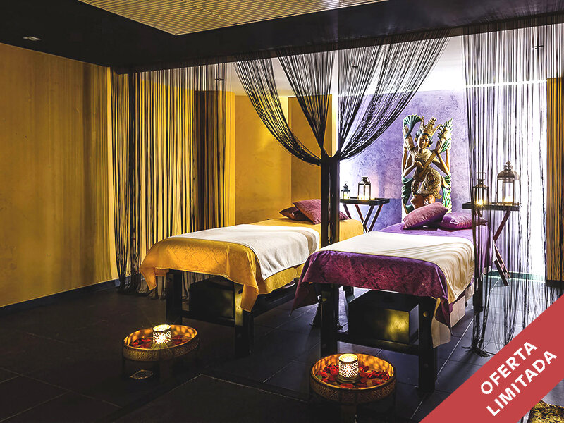 Lujosa sala de spa con dos camillas de masajes, detalles dorados, velas y una estatua tailandesa al fondo.