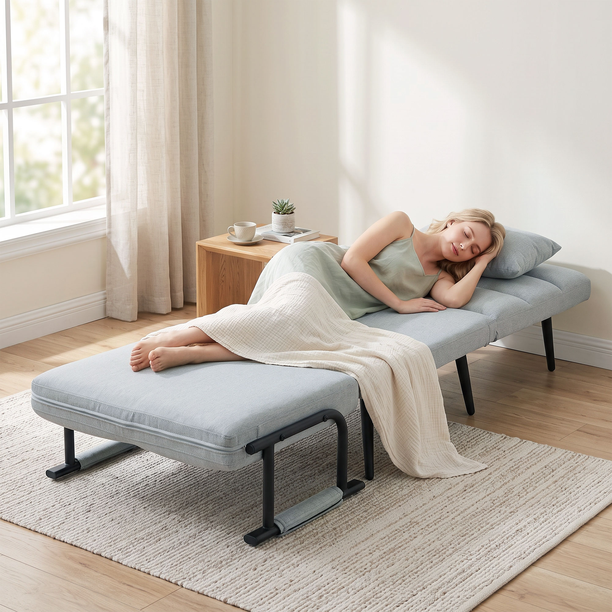 Una mujer rubia duerme plácidamente en un diván plegable azul claro con una manta crema en una habitación luminosa.