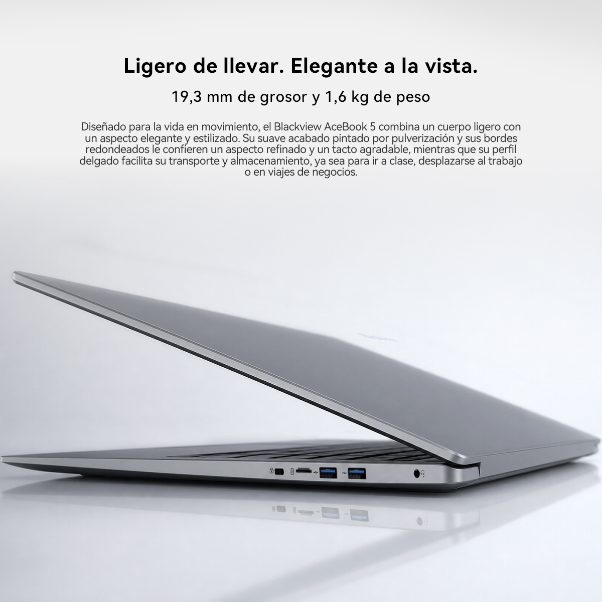 Un portátil gris y delgado sobre una superficie blanca con texto promocional en español arriba.