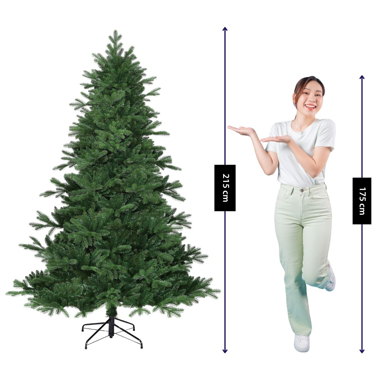 A woman in a white shirt gestures toward a tall green Christmas tree with height markers of 215 cm and 175 cm.