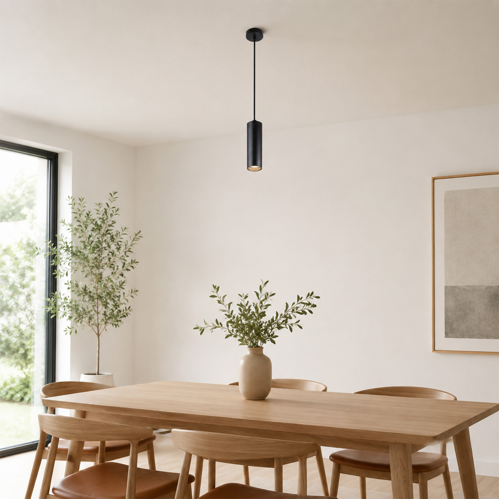 Comedor con mesa de madera, sillas, planta, cuadro enmarcado y lámpara colgante negra.