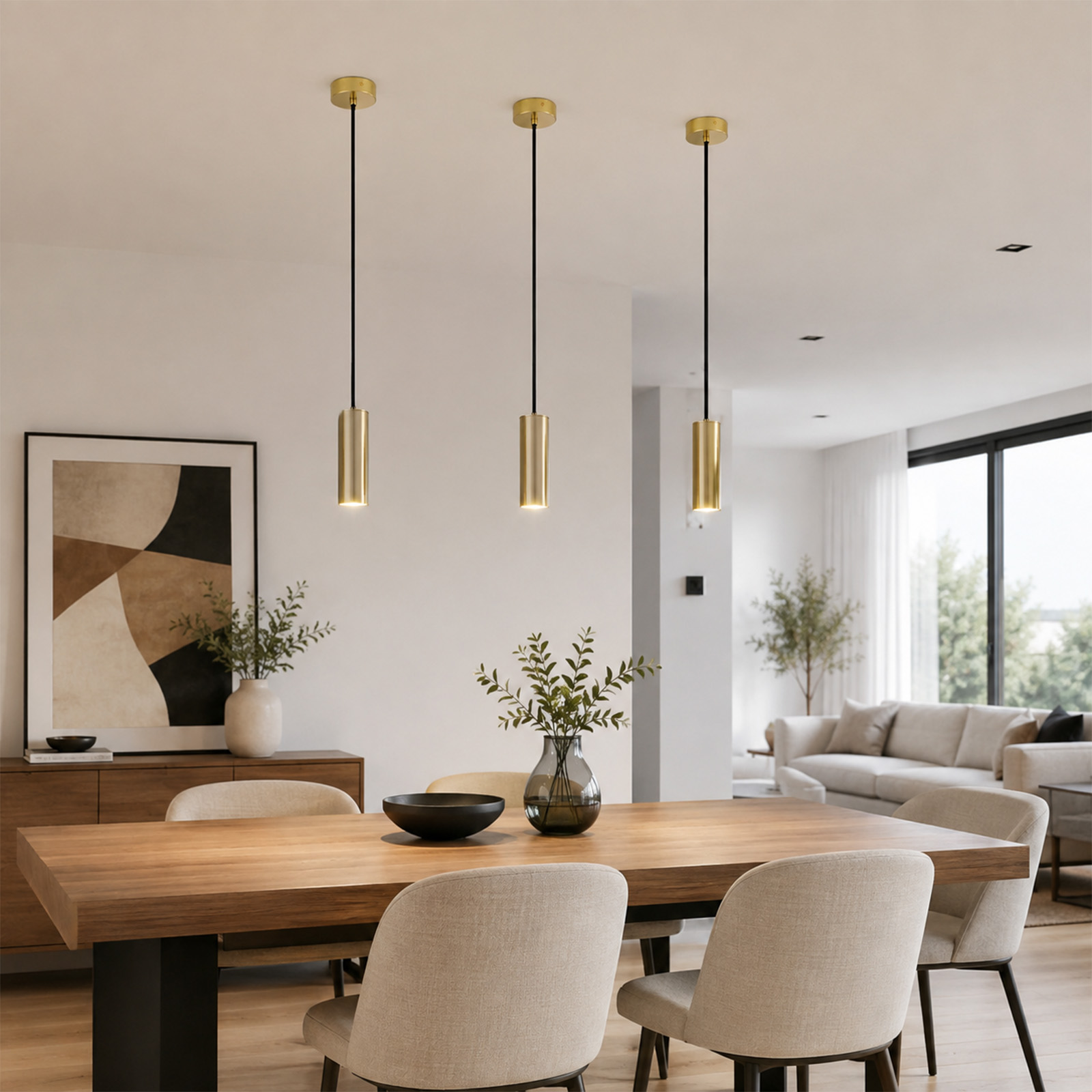 Tres lámparas colgantes doradas sobre una mesa de madera con sillas en un comedor moderno.