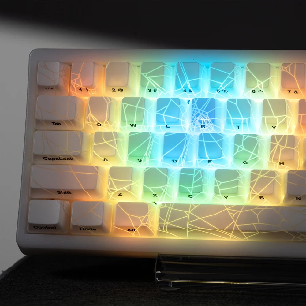 Tuşlarında ince bir örümcek ağı deseni olan, RGB arka aydınlatmalı beyaz bir mekanik klavye.