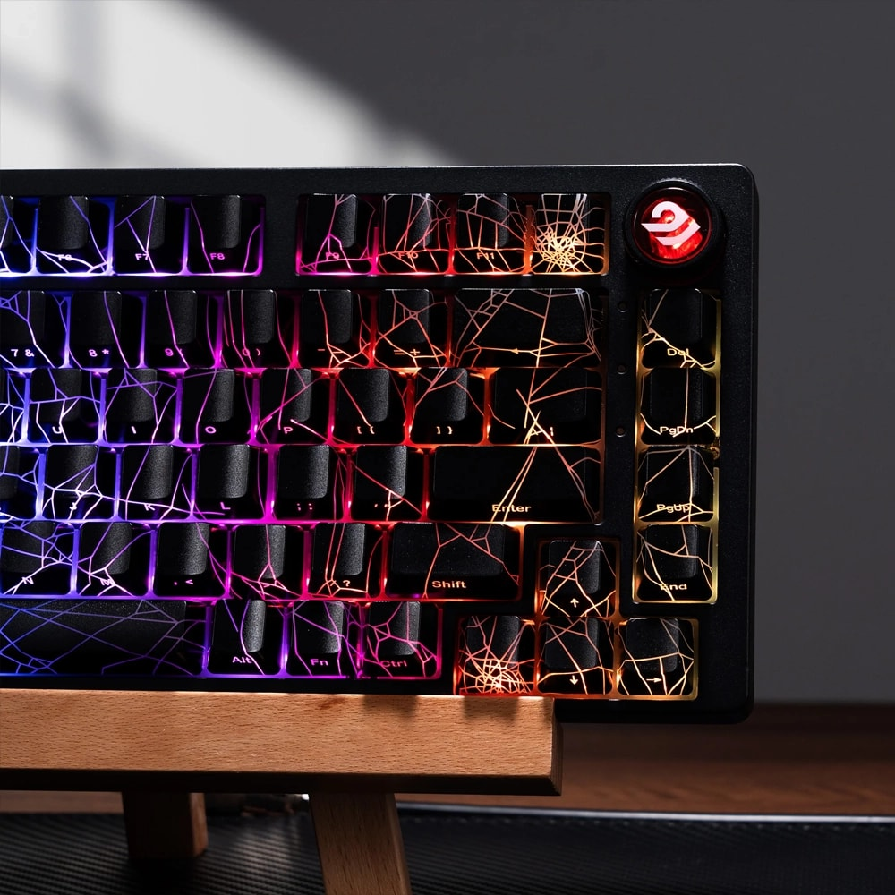 Örümcek ağı tuş kapaklarına sahip siyah mekanik klavye mavi, pembe ve turuncu RGB ışıklarla parlıyor.