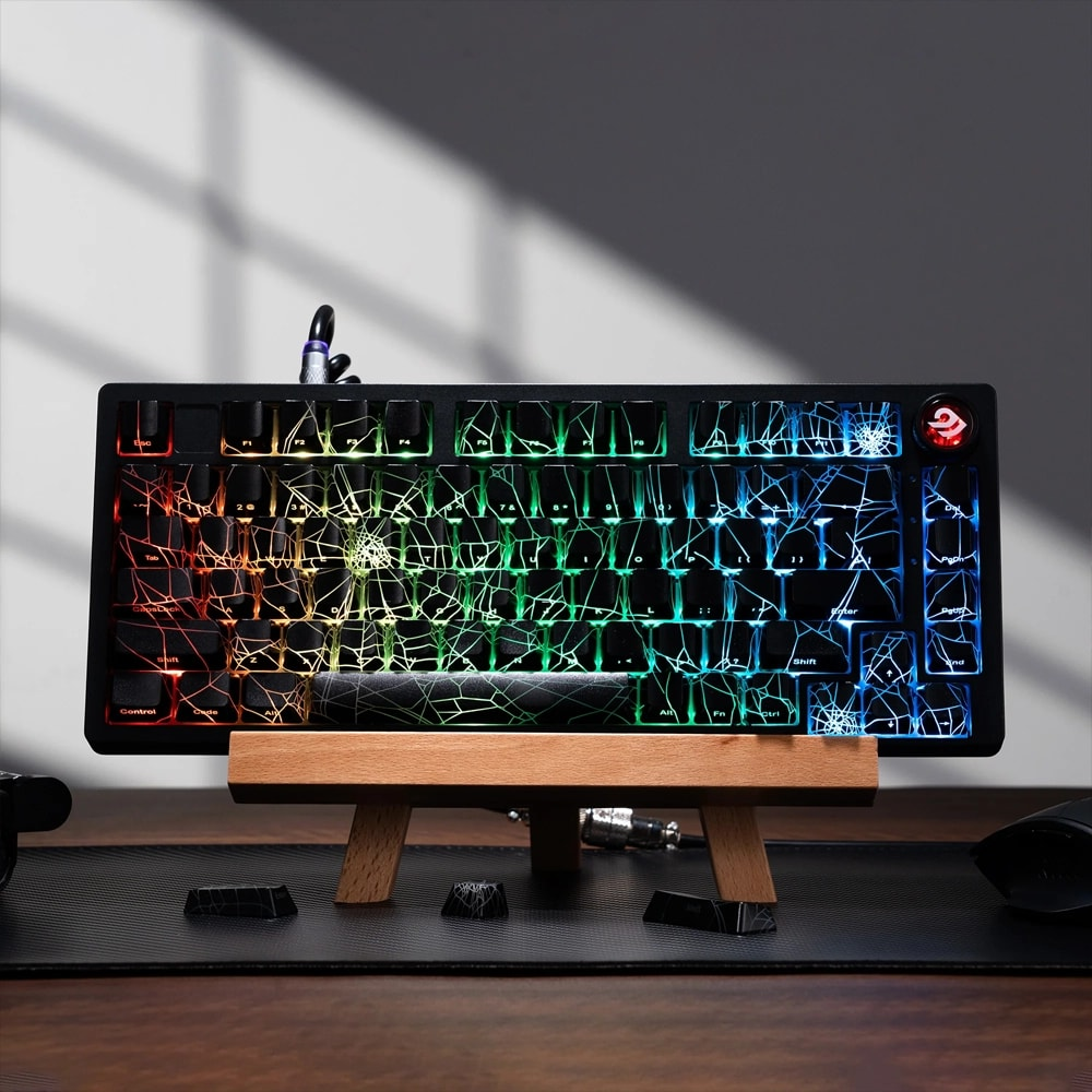 Ahşap bir stand üzerinde RGB aydınlatmalı ve örümcek ağı desenli mekanik bir klavye.