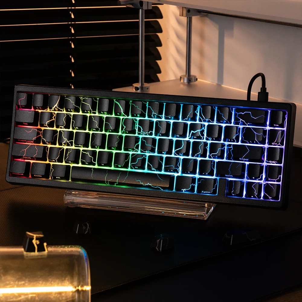 Tuşlarında şimşek deseni ve RGB arka aydınlatma olan siyah mekanik klavye, koyu renkli masa üzerinde.