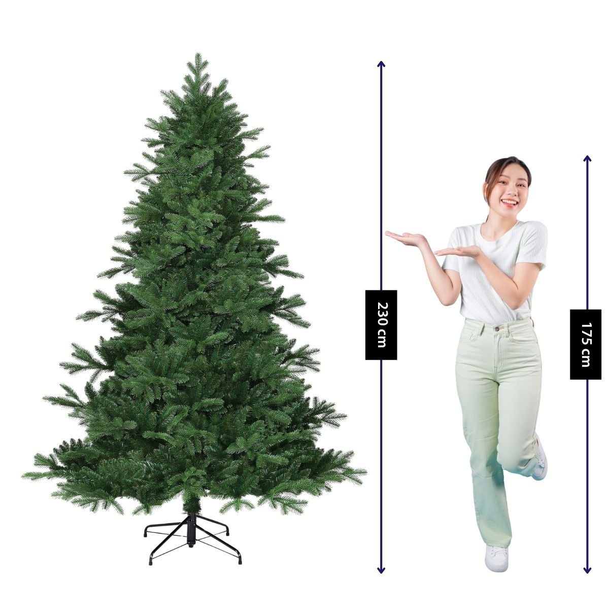 A smiling woman gestures towards a tall artificial Christmas tree showing a height of 230 cm.