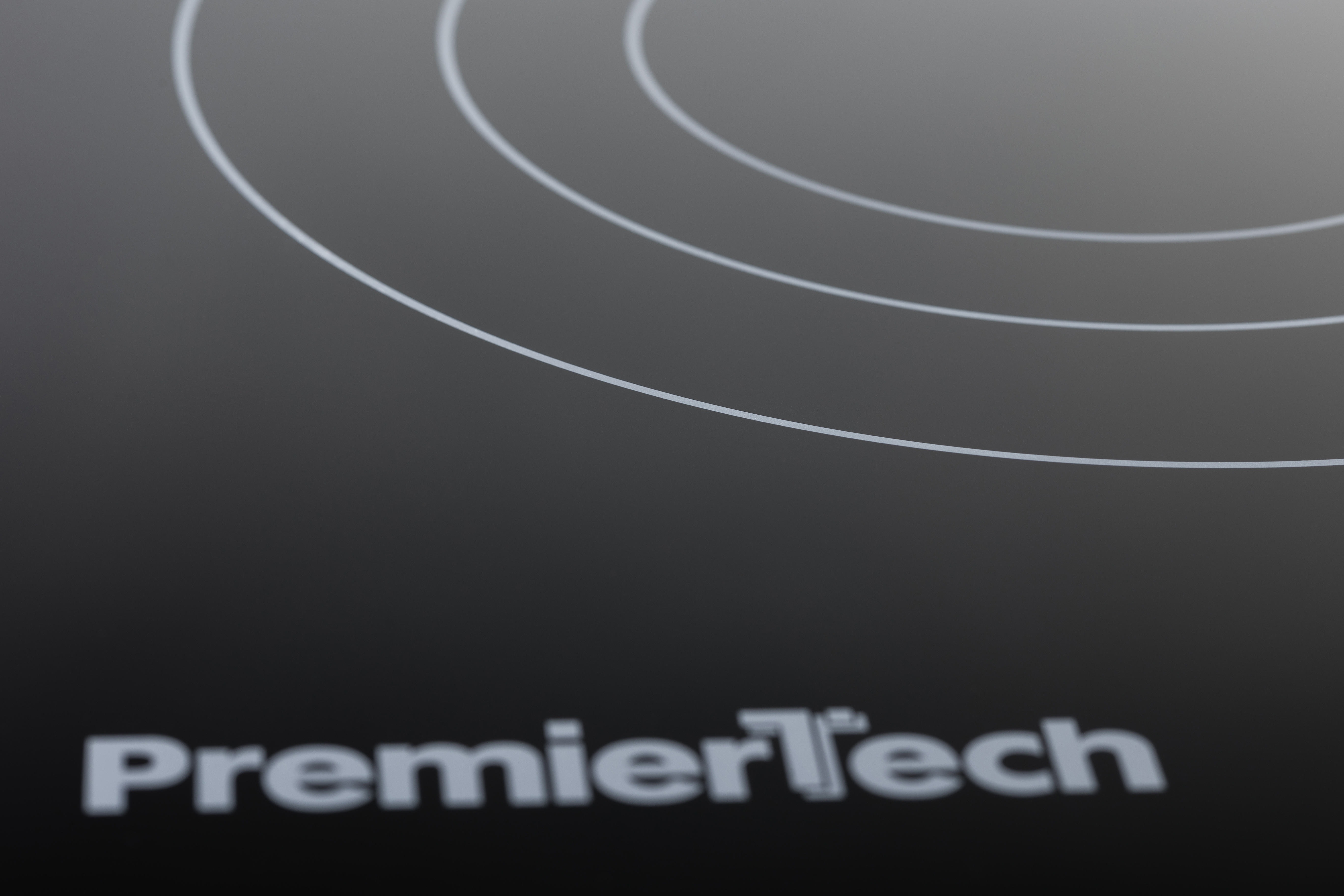 Piano cottura a induzione nero con cerchi bianchi e logo grigio PremierTech in basso.