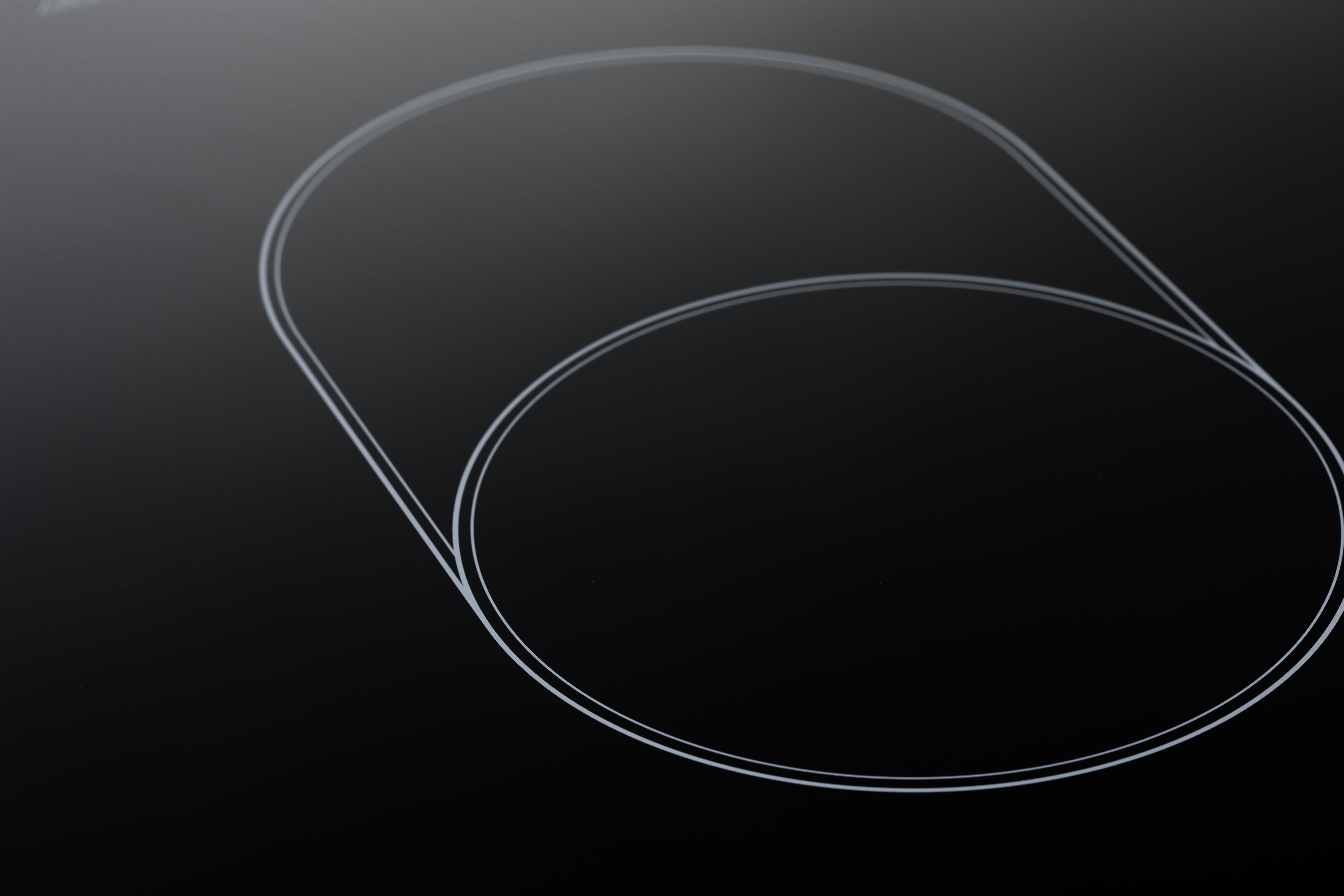 Superficie del piano cottura a induzione nero con linee di cottura circolari grigie.
