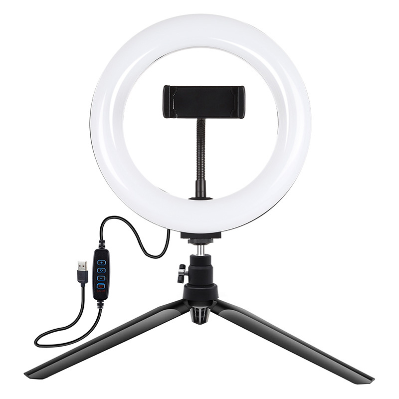Una ring light bianca su un piccolo treppiede nero con supporto per smartphone e cavo USB.