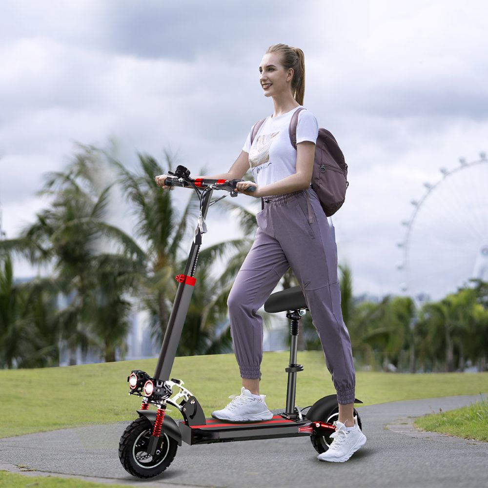 Una donna in abiti grigi guida un monopattino elettrico su un sentiero del parco con palme.