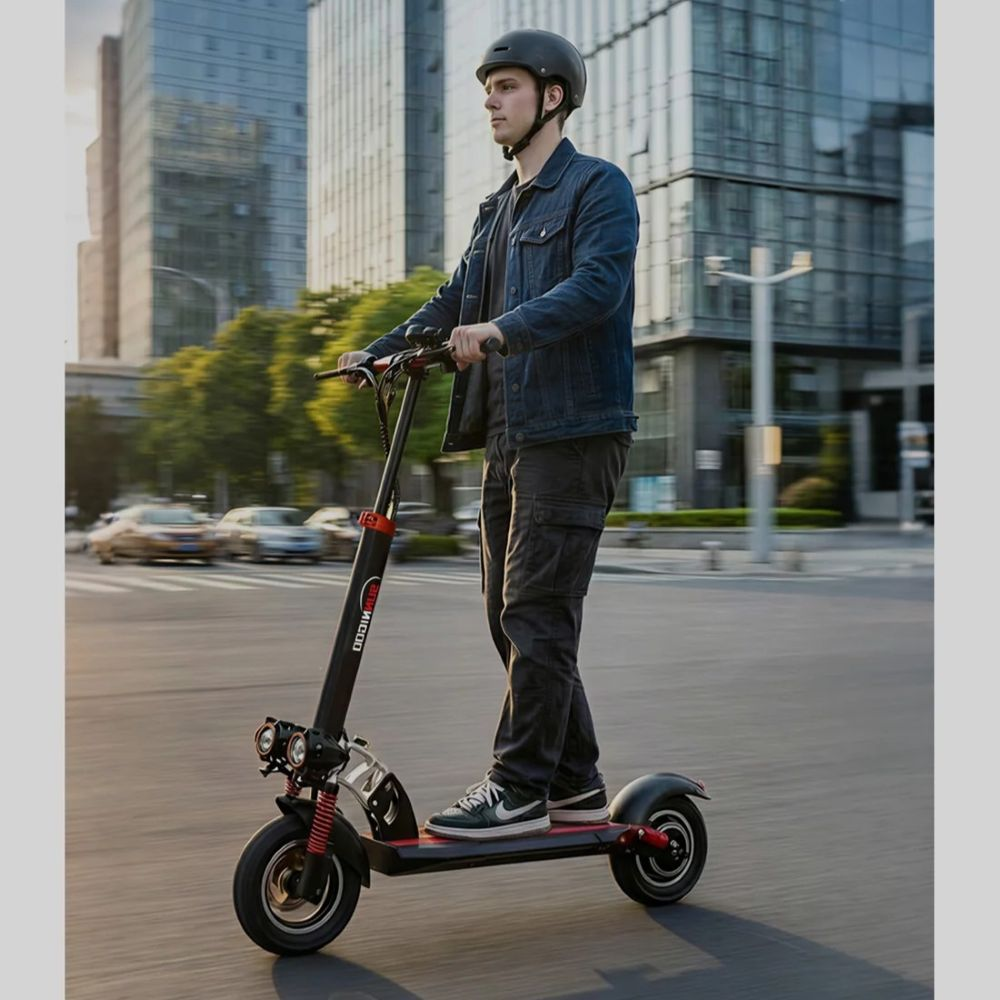 Un uomo con casco guida un monopattino elettrico nero su una moderna strada cittadina con edifici alti.
