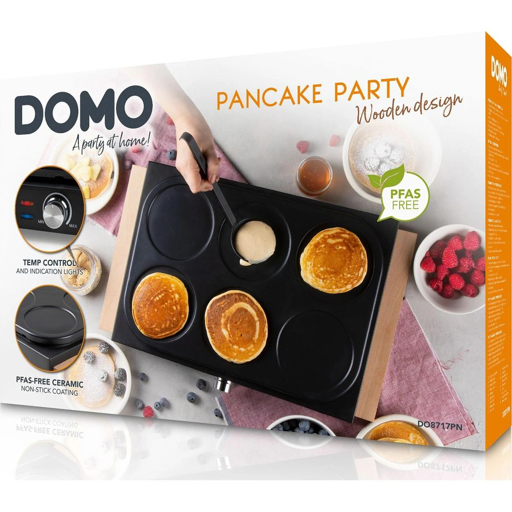 Boîte d'une crêpière noire Domo en bois, montrant trois crêpes cuites et de la pâte versée.