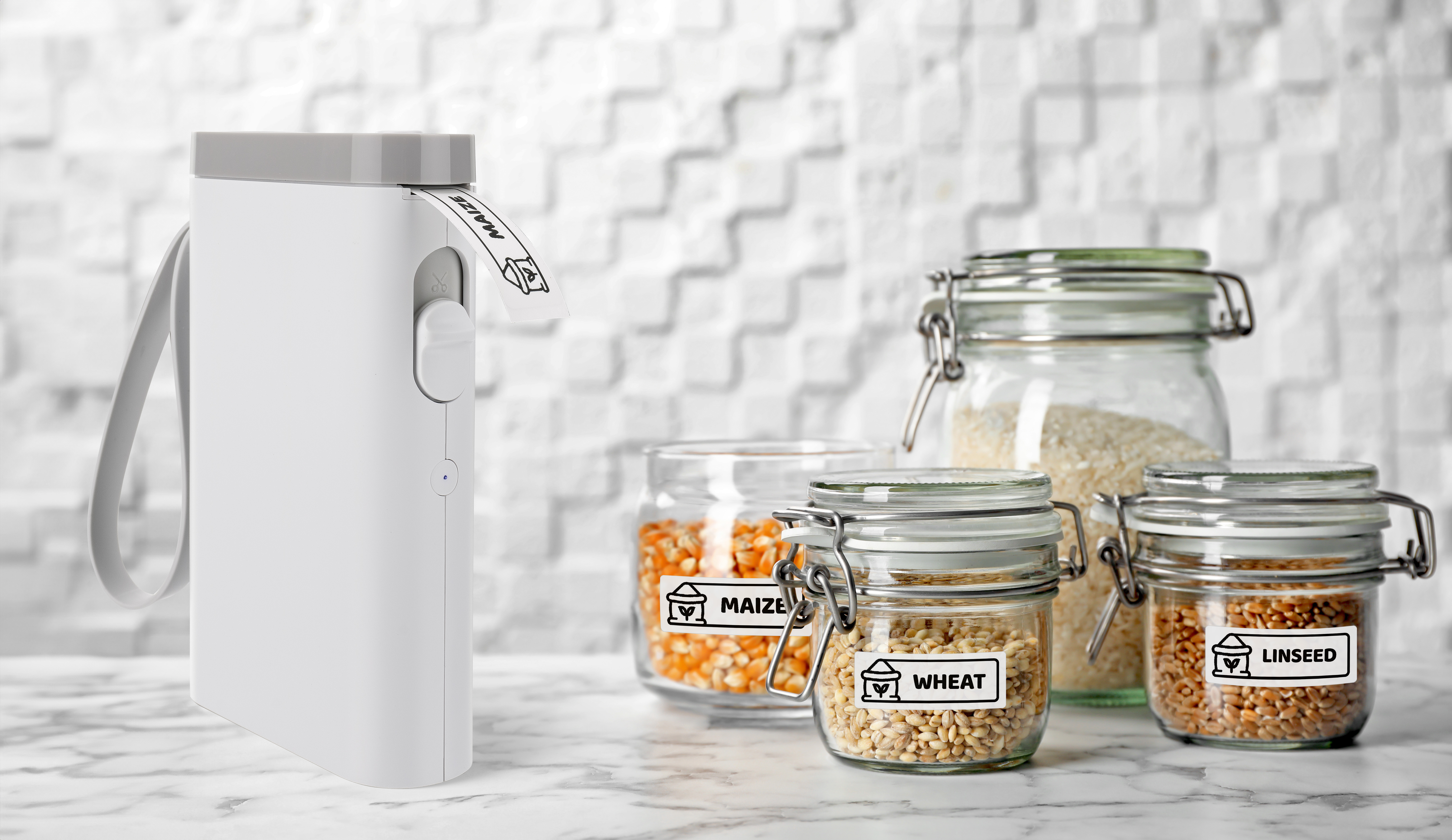 Une étiqueteuse blanche se tient à côté de bocaux en verre étiquetés de grains sur un comptoir en marbre.