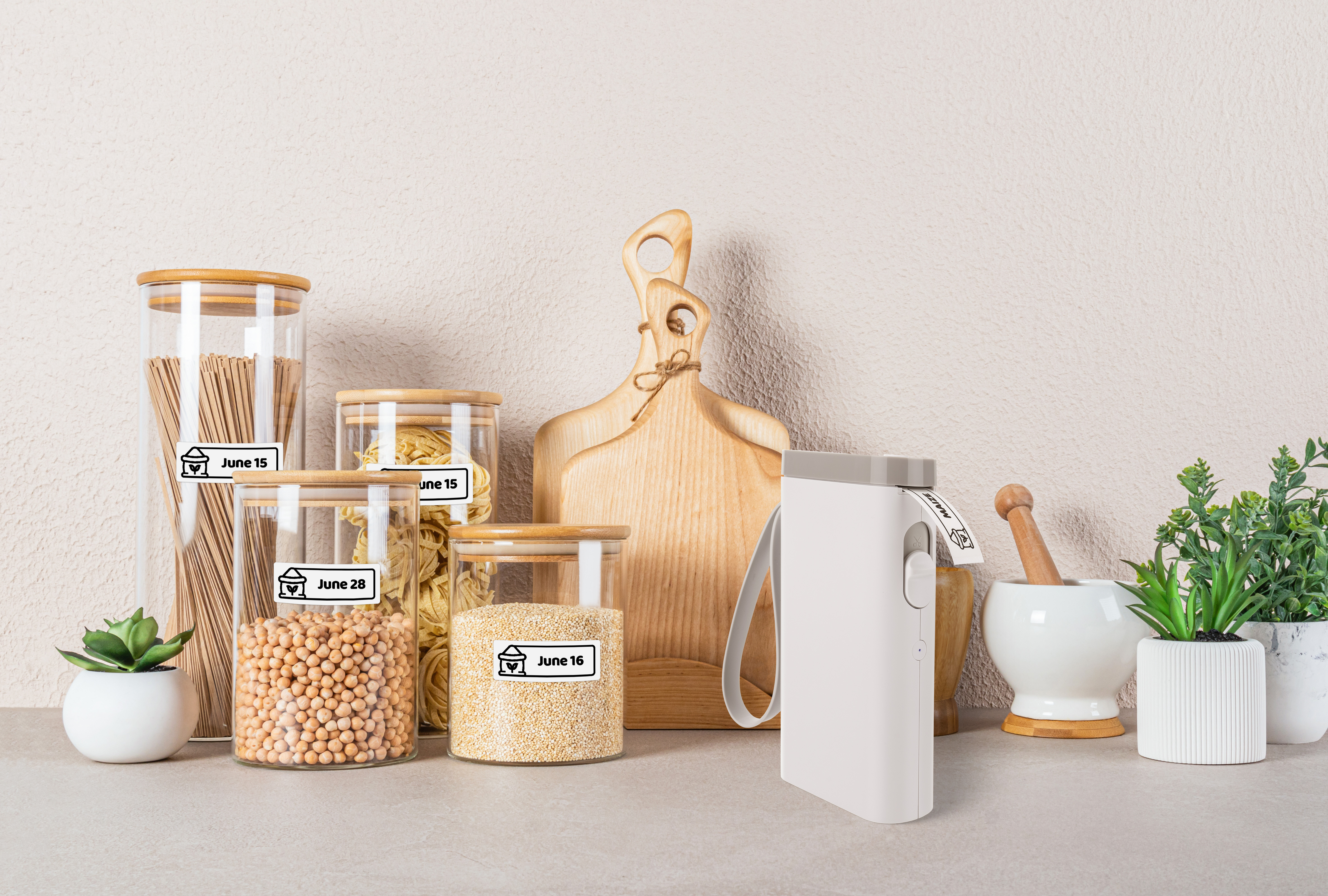 Bocaux en verre avec aliments secs étiquetés, planches à découper en bois, mortier et étiqueteuse.