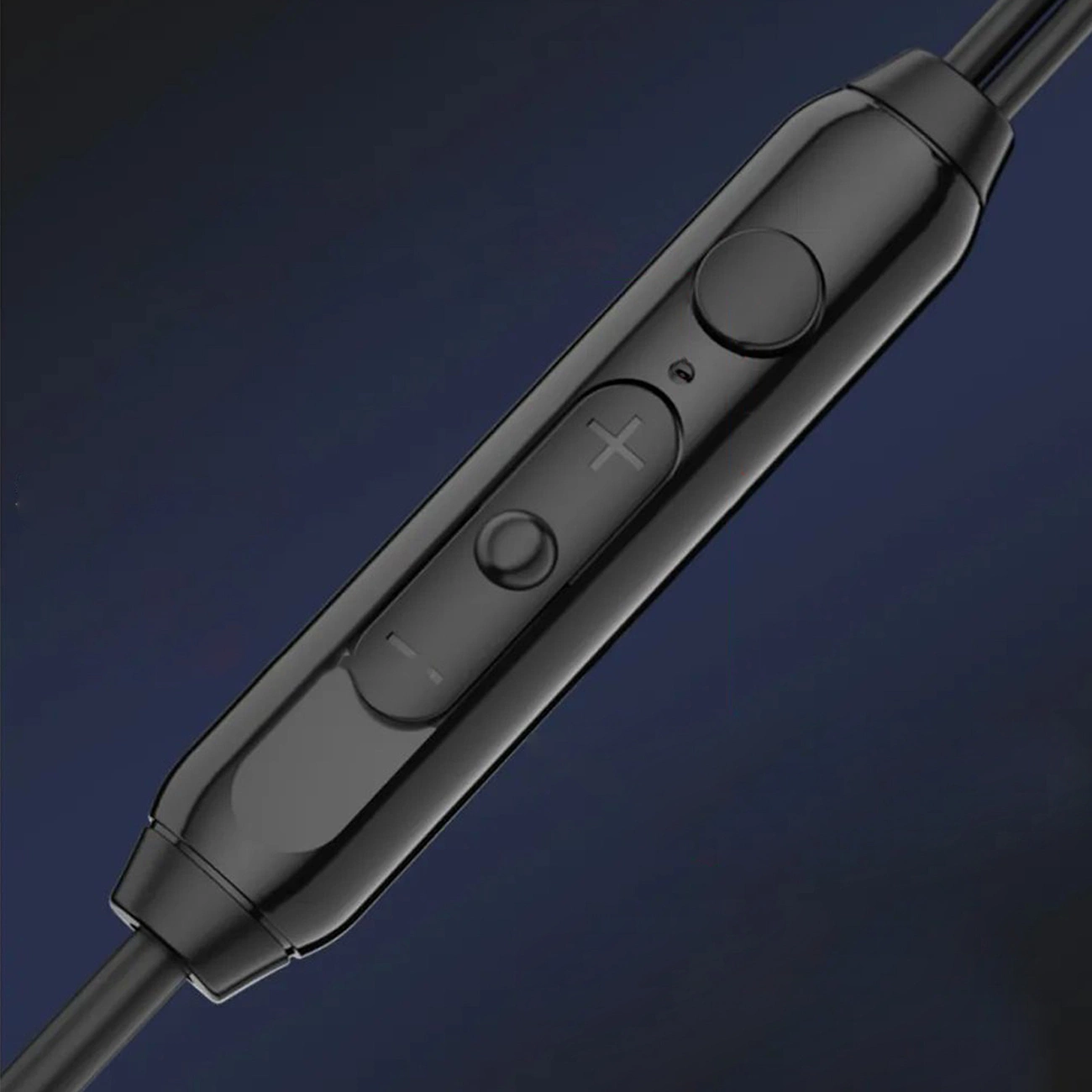 Telecomando per auricolari nero con pulsanti del volume e microfono su sfondo scuro.
