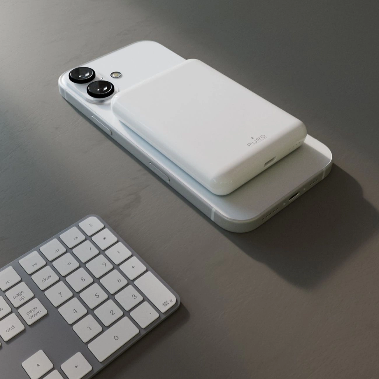 Un power bank bianco poggia sul retro di uno smartphone vicino a una tastiera.