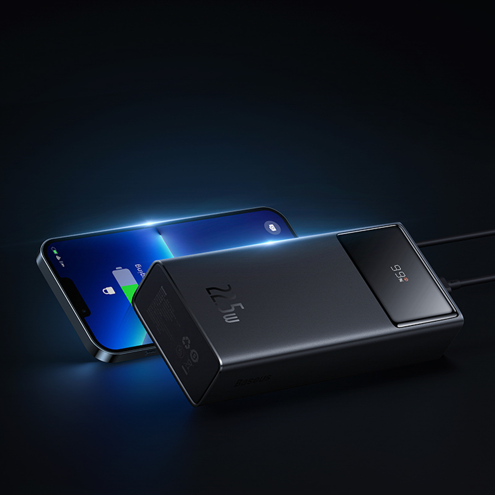 Un power bank nero e uno smartphone con schermo blu poggiano su una superficie scura.