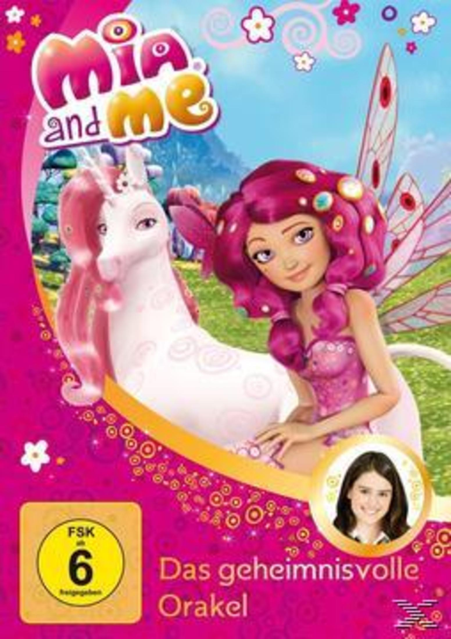 Mia mit rosafarbenen Haaren und Feenflügeln sitzt neben einem weißen Einhorn auf einer bunten Wiese.