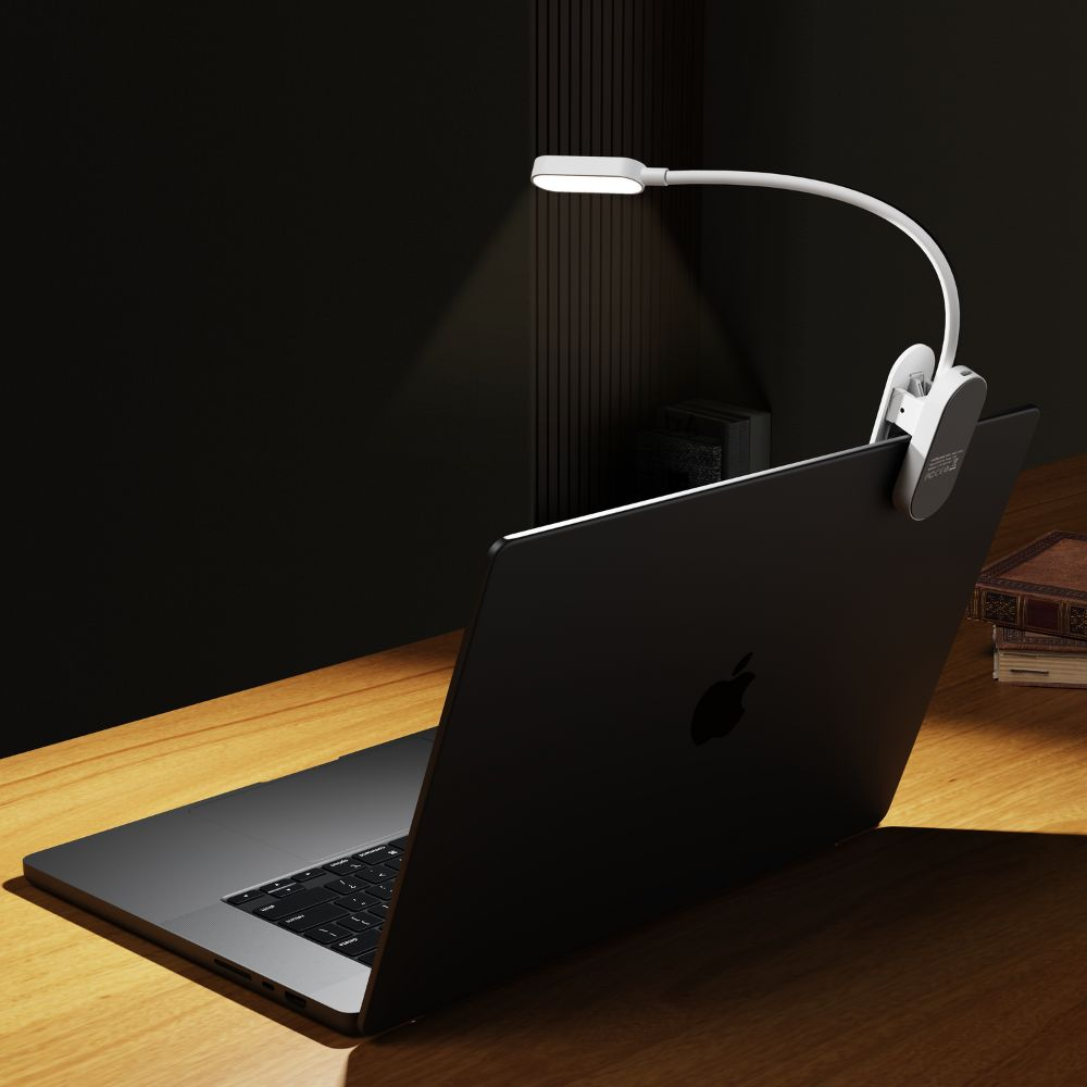 Eine kleine weiße LED-Lampe ist am Laptop auf einem Holztisch befestigt.