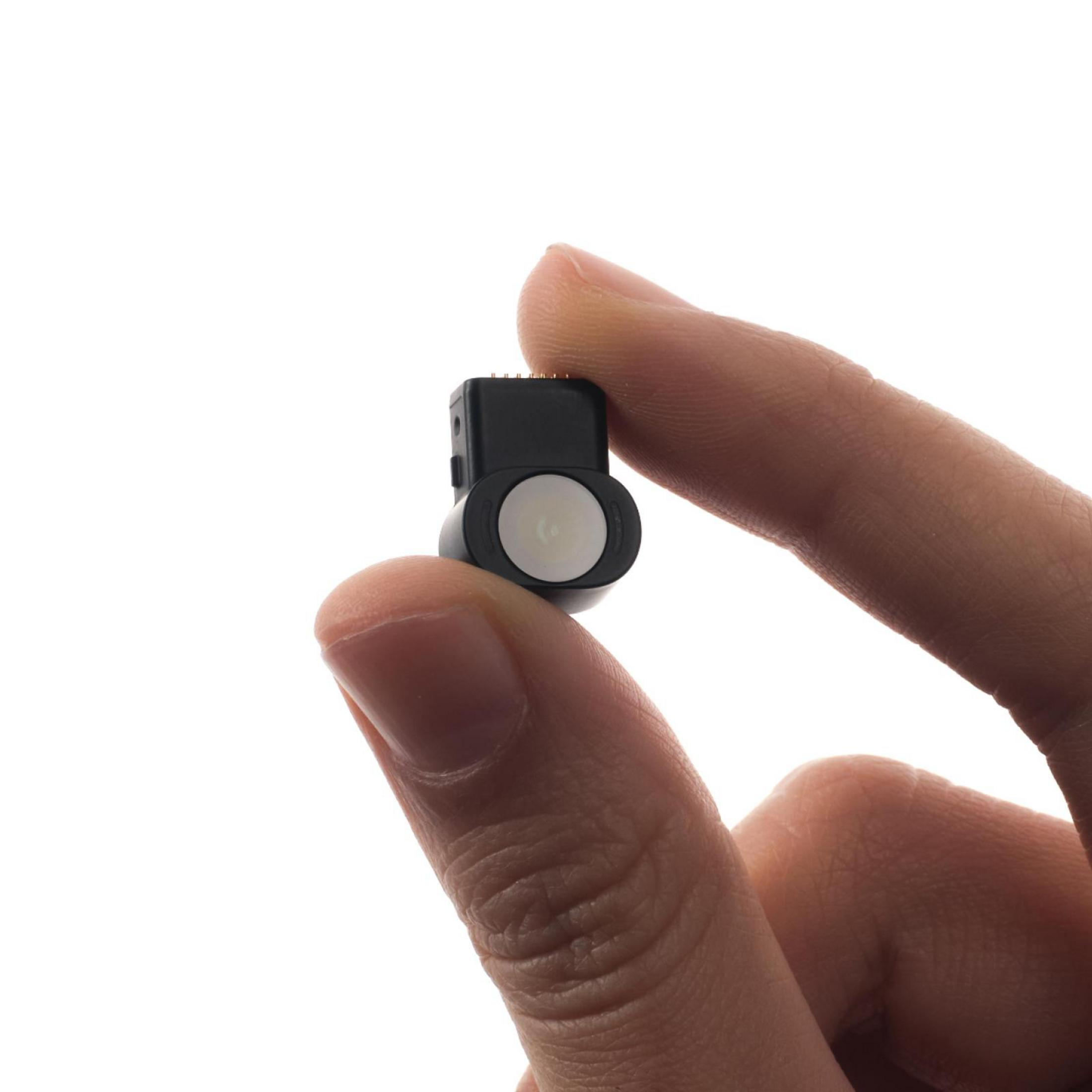Una mano tiene un piccolo componente elettronico nero con una lente bianca rotonda su sfondo bianco.