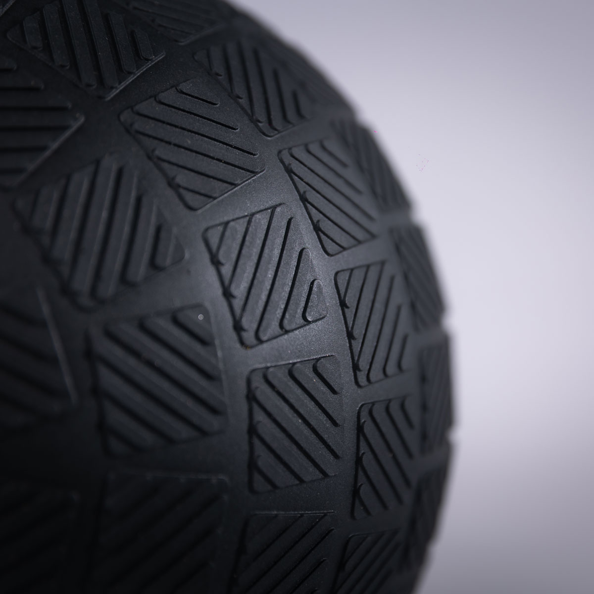 Primer plano de un balón medicinal negro texturizado sobre fondo gris.