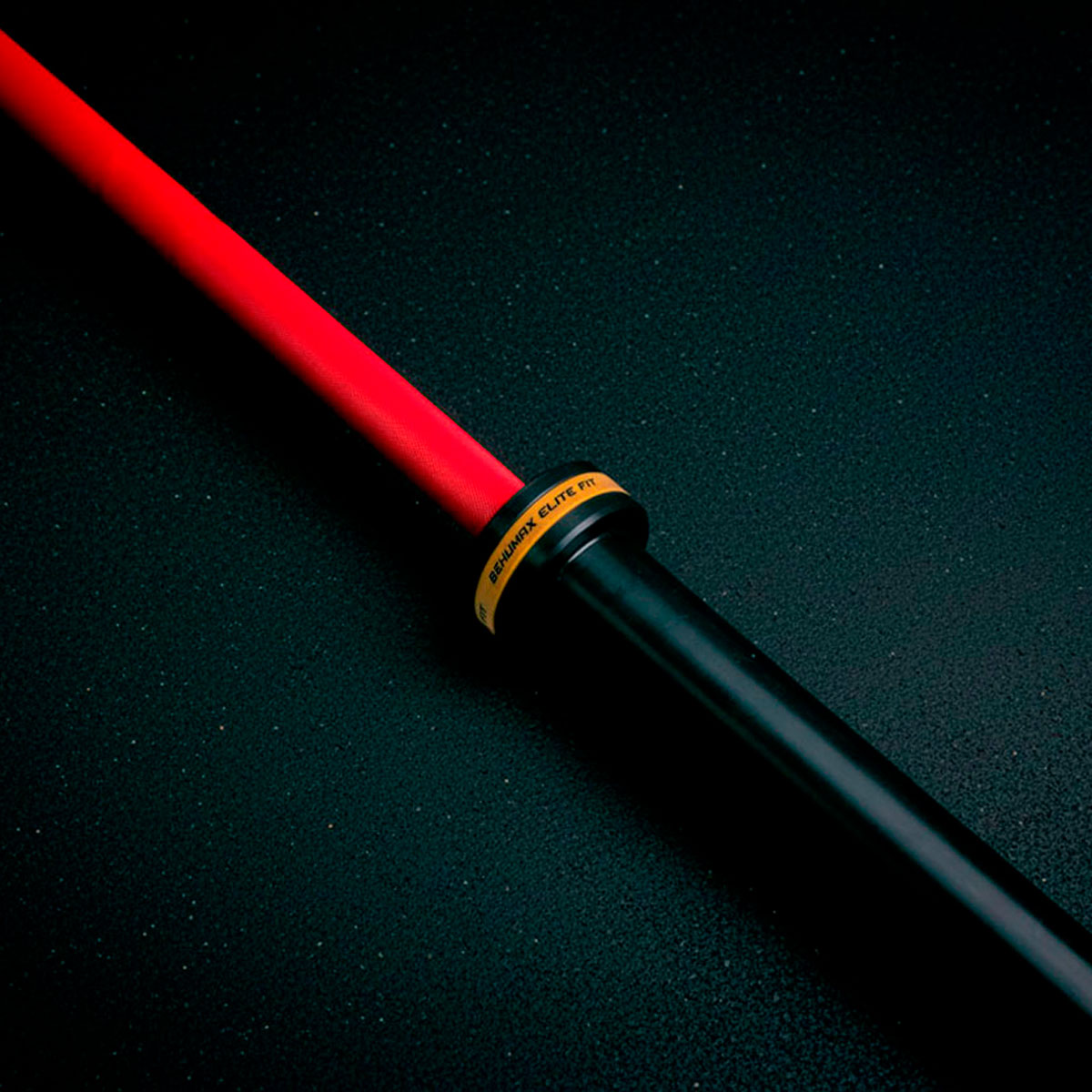 Una barra negra y roja con un anillo de texto amarillo yace diagonalmente sobre una superficie oscura.