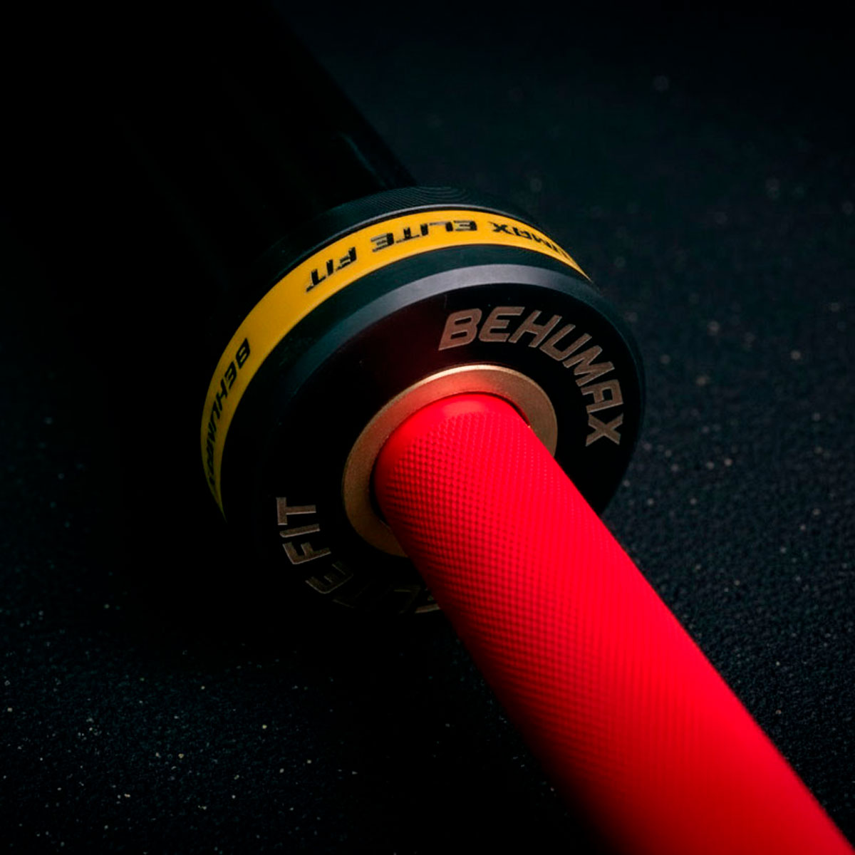 Una barra roja con un collar Behumax Elite Fit descansa sobre un suelo oscuro.
