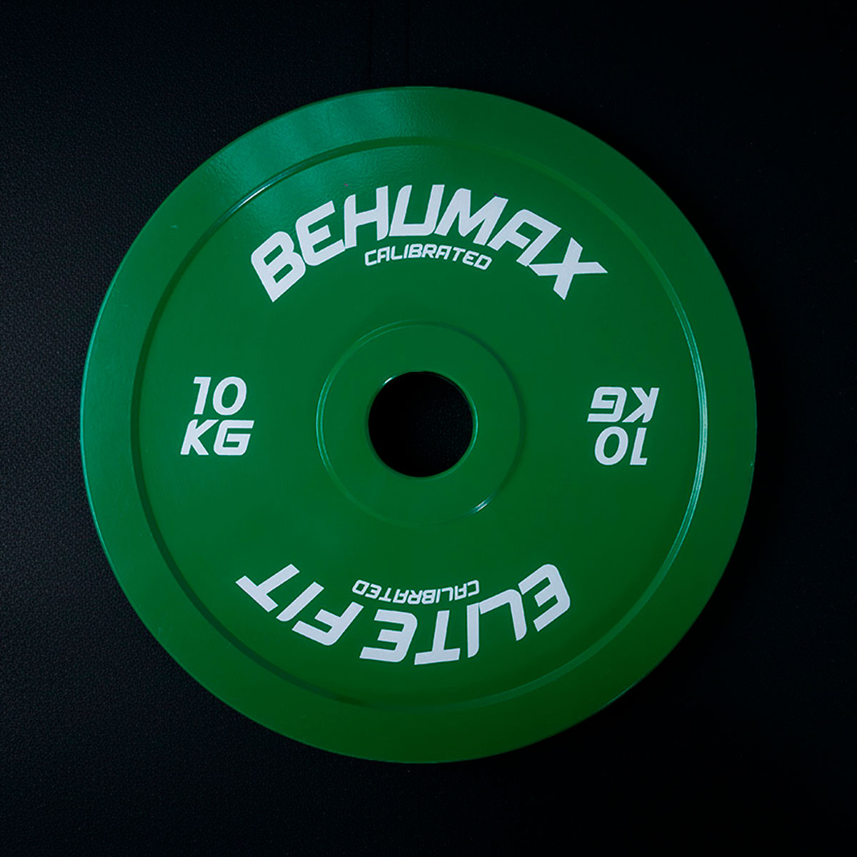 Un disco de peso verde de 10 kg con letras blancas sobre fondo negro.