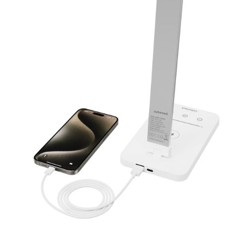 Ein Smartphone lädt an einer weißen Lampe mit Ladeanschluss und Kabel.