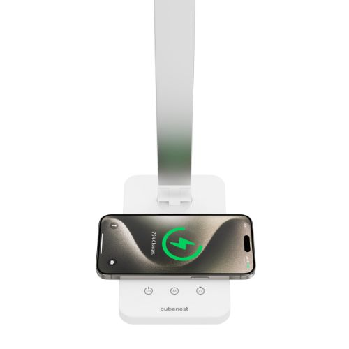 Ein weißes Schreibtischlampen-Basisgerät lädt ein Smartphone kabellos auf, mit grünem Ladesymbol.