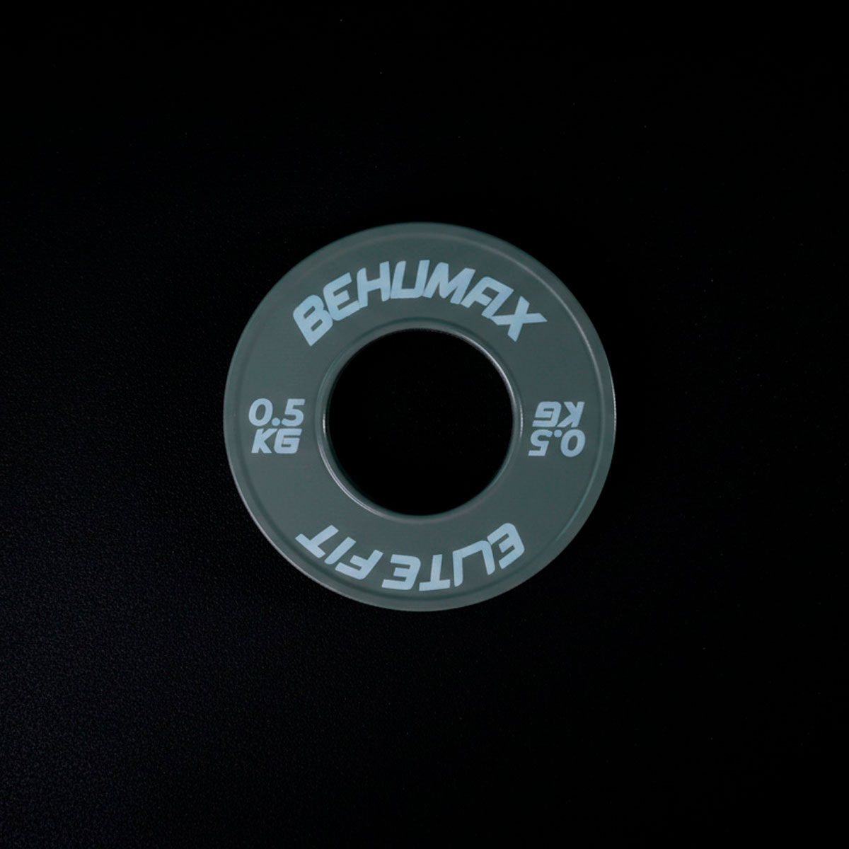 Un disco de peso gris de 0.5 kg Behumax Elite Fit centrado en un fondo negro.
